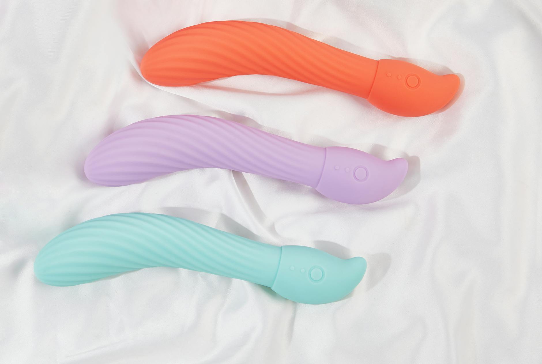A hand holding an orange vibrator against a minimalistic purple backdrop, showcasing modern sensuality