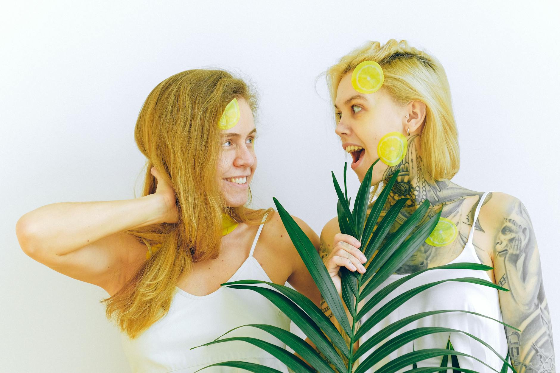 Two smiling women with lemon slices expressing joy indoors