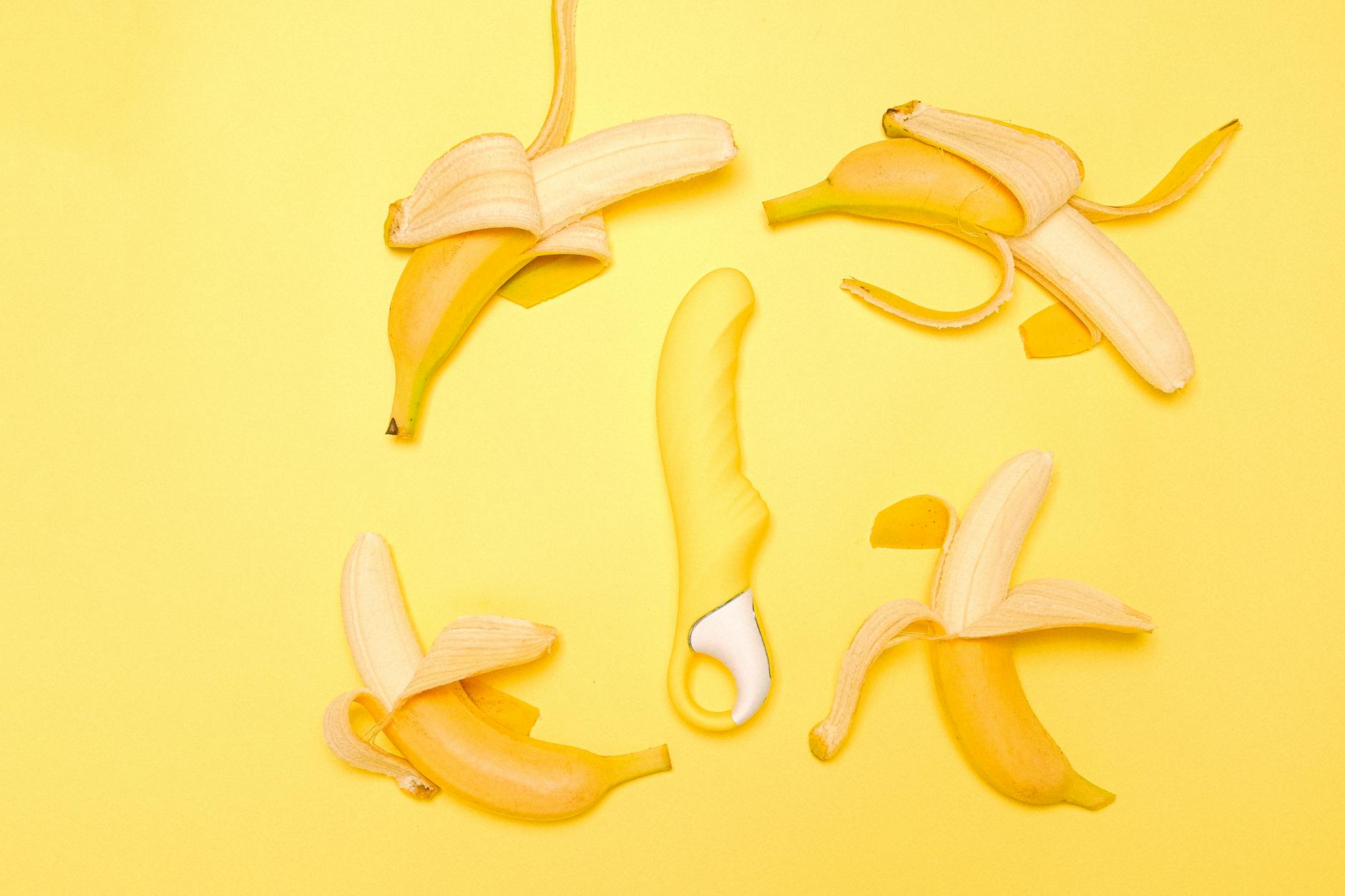 Yellow silicone lemon clitoral vibrator surrounded by fresh lemons on bright background