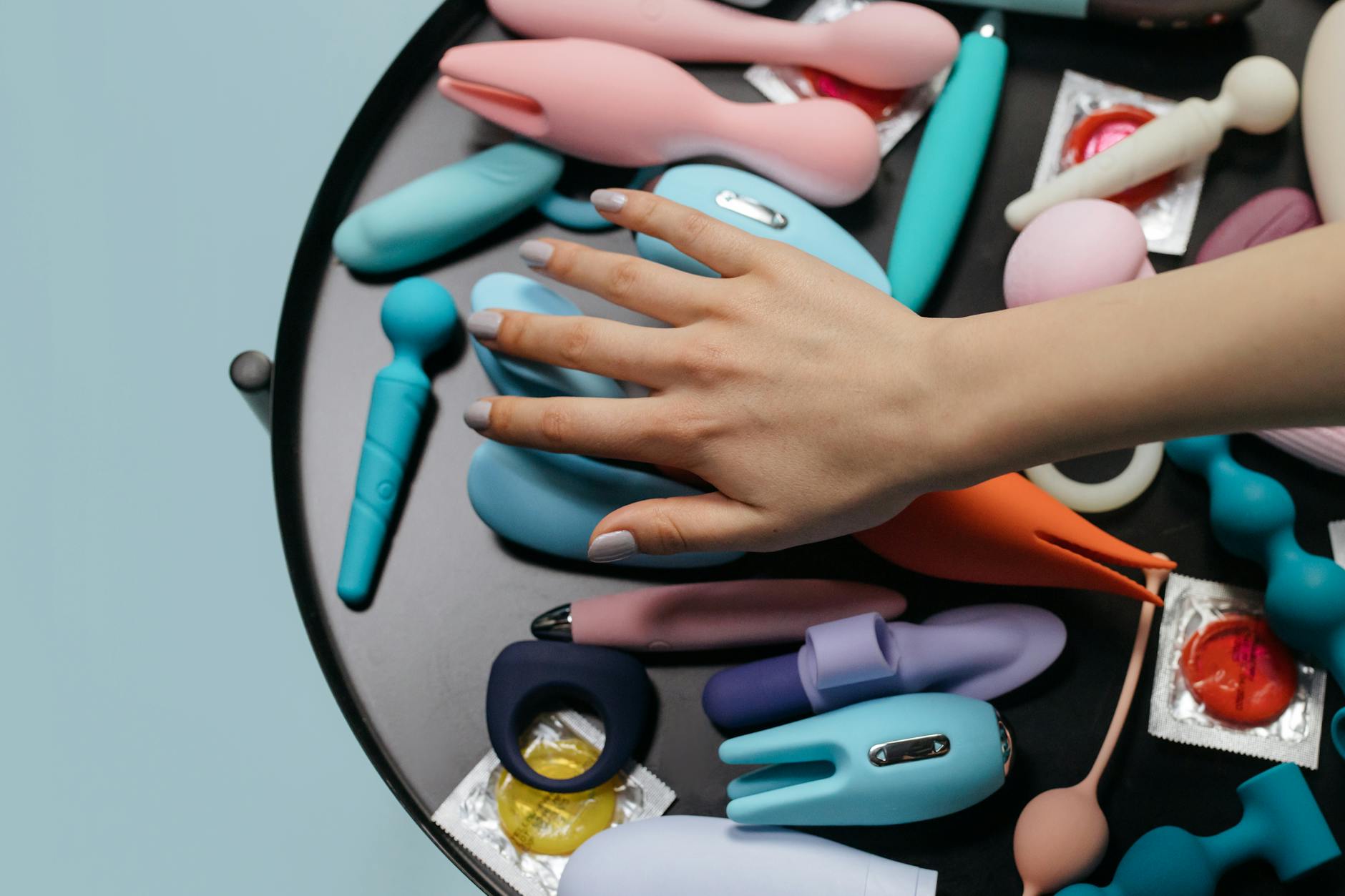 Hands holding pastel silicone vibrators, symbolizing postpartum pleasure recovery and self-care