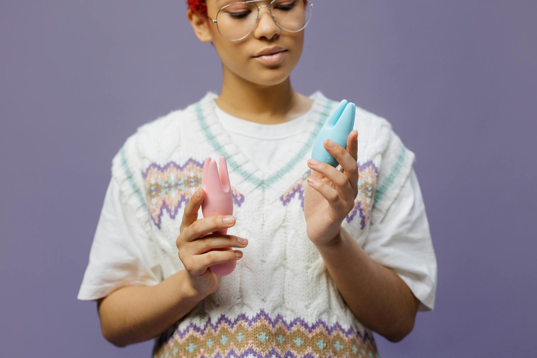 Woman thoughtfully holding intimate wellness devices during postpartum recovery exploration