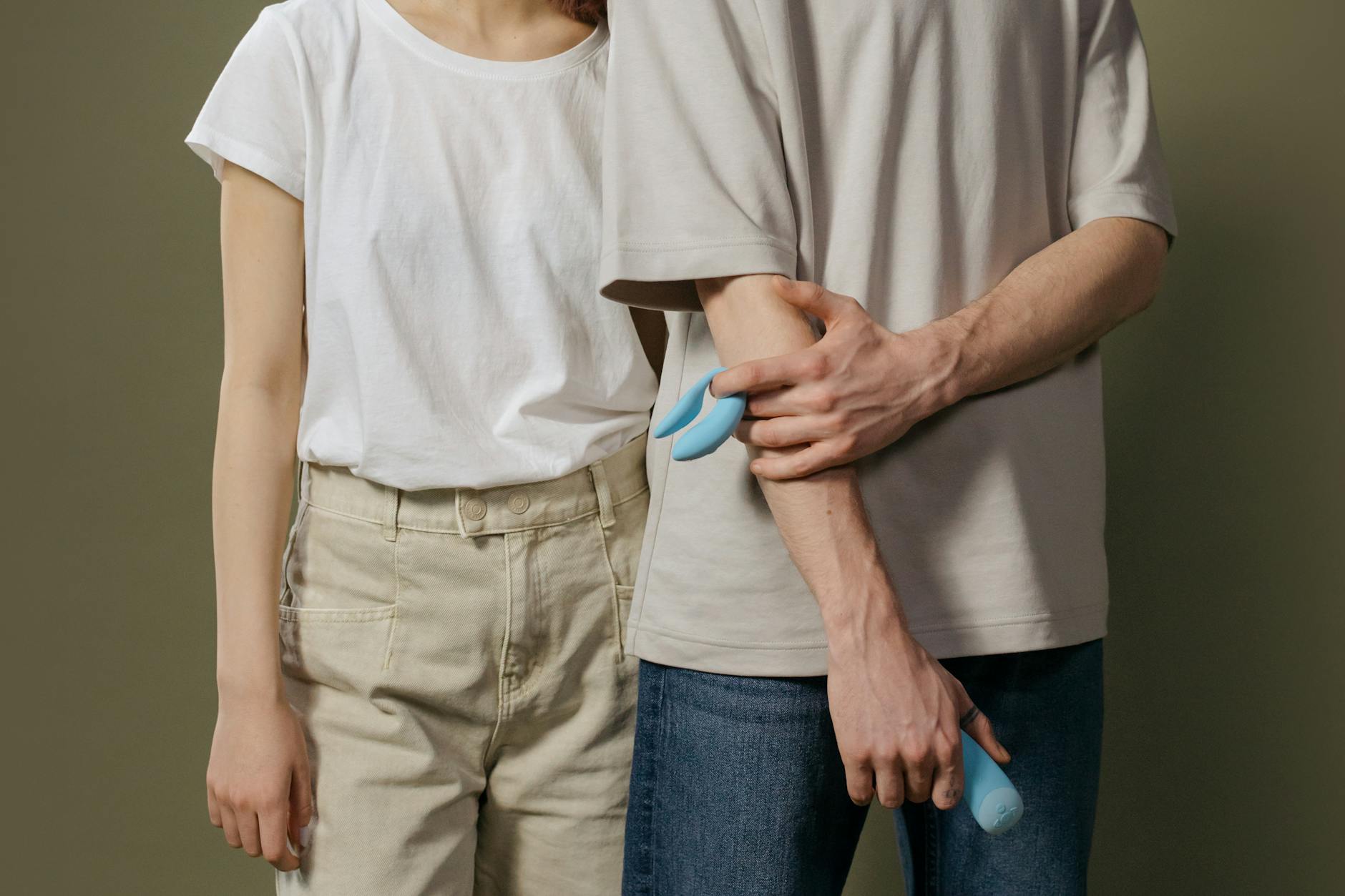 A young couple standing together indoors, exploring intimacy with modern pleasure tools.