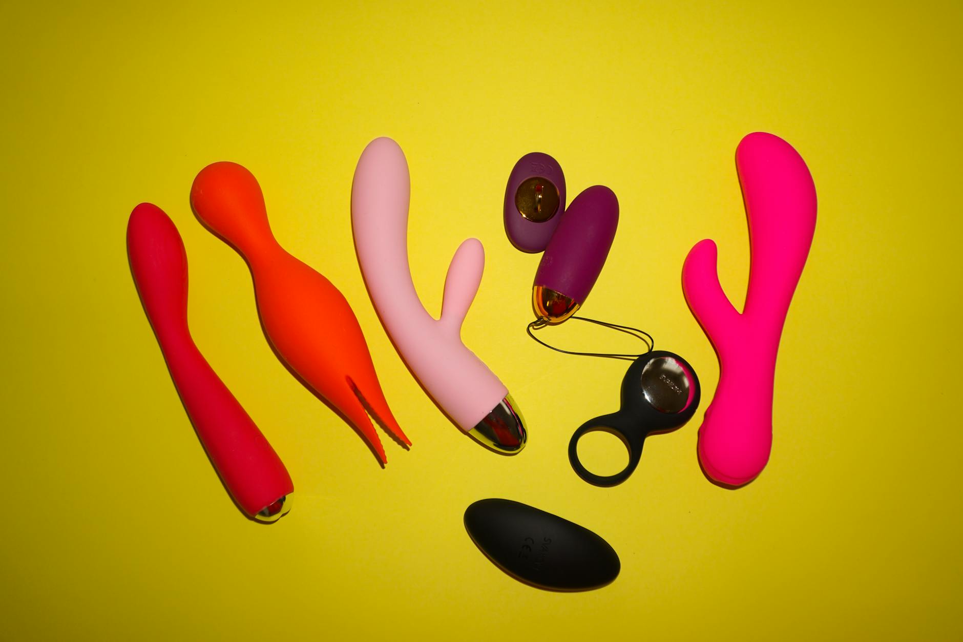 Bunte Arrangement von Vibratoren auf leuchtend gelbem Hintergrund, verschiedene Formen und Designs zeigend