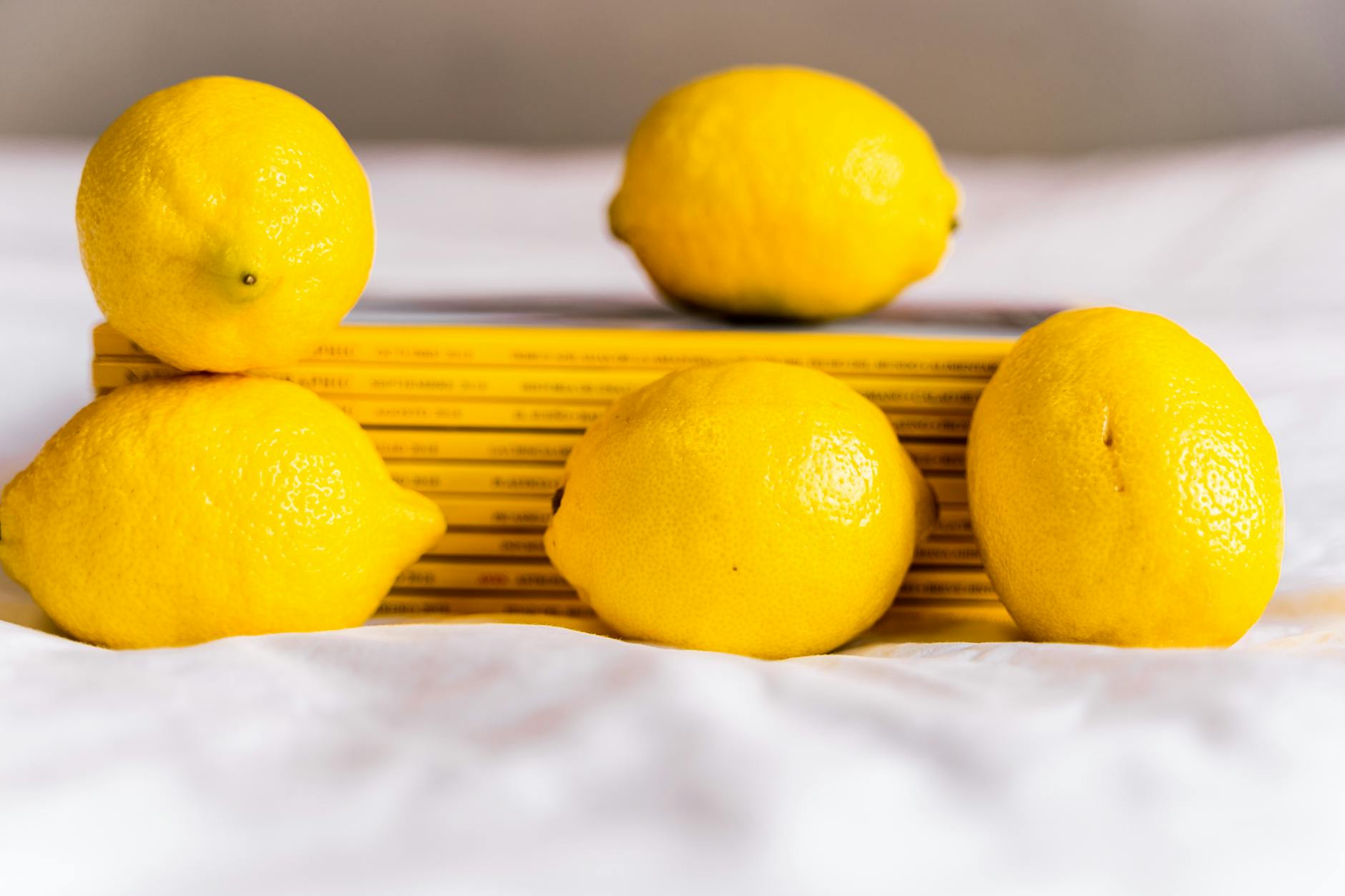 Fresh lemons arranged with books on white fabric, representing clarity and choice
